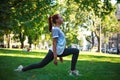 Young woman in city park on green grass doing stretching fitness exercises outdoors Royalty Free Stock Photo