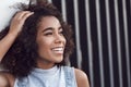 Young woman in the city street leaning on wall looking aside touching hair laughing close-up Royalty Free Stock Photo