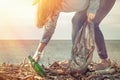 A young woman on a clean-up of the coastal area, collecting garbage. Sea and sky in the background. Earth day and ecology. Light Royalty Free Stock Photo