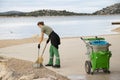 Young woman cleaner, working for city service, on her morning duty routine cleaning the beach in Vodice, Croatia