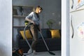 Young woman is cleaning the apartment with vacuum cleaner. Housekeeper vacuums the living room Royalty Free Stock Photo