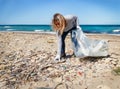 Young woman cleaning beach area from plastic bottles Royalty Free Stock Photo