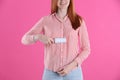 Young woman cleaning clothes with lint roller on pink background, closeup Royalty Free Stock Photo