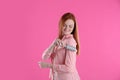 Young woman cleaning clothes with lint roller on pink background Royalty Free Stock Photo