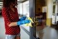 Young woman cleaning the door handle with a rag wearing blue rubber gloves. Business office disinfection during coronavirus Royalty Free Stock Photo