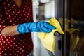 Young woman cleaning the door handle with a rag wearing blue rubber gloves. Business office disinfection during coronavirus Royalty Free Stock Photo