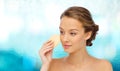 Young woman cleaning face with exfoliating sponge