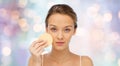 Young woman cleaning face with exfoliating sponge