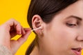 Young woman cleaning her ears with cotton sticks on yellow background Royalty Free Stock Photo