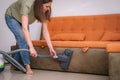 Young woman cleaning in the house, vacuuming sofa, housework, family cleans the room at home. Royalty Free Stock Photo