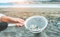 Young woman cleaning microplastics from sand on the beach - Environmental problem, pollution and ecolosystem warning concept - Royalty Free Stock Photo