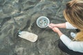 Young woman cleaning microplastics from sand on the beach - Environmental problem, pollution and ecolosystem warning concept - Royalty Free Stock Photo