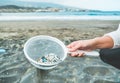 Young woman cleaning microplastics from sand on the beach - Environmental problem, pollution and ecolosystem warning concept -