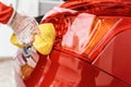 Young woman cleaning rear lights of her car, closeup detail on hand in glove holding yellow sponge Royalty Free Stock Photo