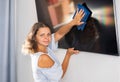 Young woman cleaning TV screen at home