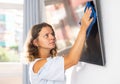 Young woman cleaning TV screen at home