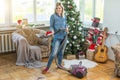 Young woman cleaning with vacuum cleaner, vacuuming under Christmas Tree needles with New Years ornaments on hardwood Royalty Free Stock Photo