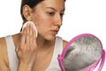 A young woman cleans her face with problematic skin