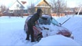 Young woman cleans snow from car