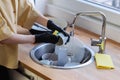 A young woman cleans up in the kitchen, washing dishes.