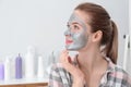 Young woman with cleansing mask on her face in bathroom. Skin care Royalty Free Stock Photo