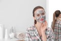 Young woman with cleansing mask on her face in bathroom, space for text Royalty Free Stock Photo