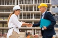 Woman client shaking hand with builder at construction site