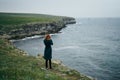 Young woman on a cliff of a mountain near the sea, wind, sadness Royalty Free Stock Photo