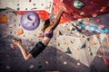 Young woman climbing artificial boulder indoors