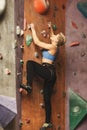 Young woman climbing artificial rock wall at gym Royalty Free Stock Photo