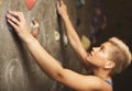 Young woman climbing artificial rock wall at gym Royalty Free Stock Photo