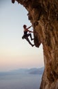 Young woman climbing challenging route at sunset