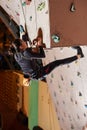 Young woman climbing up on practice wall in gym Royalty Free Stock Photo