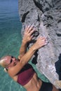 A young woman climbing up a rock face Royalty Free Stock Photo