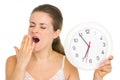 Young woman with clock yawing after sleep