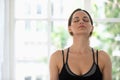 Young woman with closed eyes practicing yoga, meditating indoors Royalty Free Stock Photo