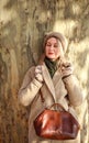 Young woman in a coat  in city spring park enjoys walk on sunny day Royalty Free Stock Photo