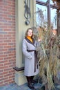 A young woman in a coat stands near a decorative composition of dry cane Royalty Free Stock Photo