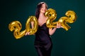 Young woman in cocktail dress with bright make-up celebrating New Year 2022 and holding golden balloons 2022 in hands on Royalty Free Stock Photo