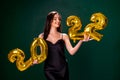 Young woman in cocktail dress with bright make-up celebrating New Year 2022 and holding golden balloons 2022 in hands on Royalty Free Stock Photo