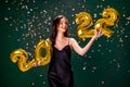 Young woman in cocktail dress celebrating New Year 2022 and holding golden balloons 2022 Royalty Free Stock Photo