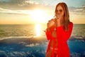 Young woman with coctail in summer dress standing on a pool and sea background . Sunset Royalty Free Stock Photo