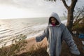 Young woman on cold autumn seashore posing at camera