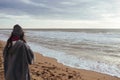 Young woman on cold autumn seashore posing at camera