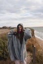 Young woman on cold autumn seashore posing at camera