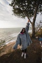 Young woman on cold autumn seashore posing at camera