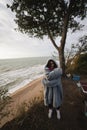 Young woman on cold autumn seashore posing at camera