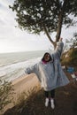 Young woman on cold autumn seashore posing at camera