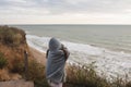 Young woman on cold autumn seashore posing at camera