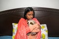 A young woman with a cold with a blanket who suffers from cold at home